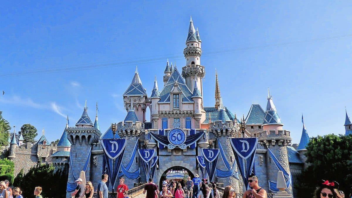 Sleeping Beauty Castle at Disneyland in Anaheim, California, with visitors walking below it under a blue sky