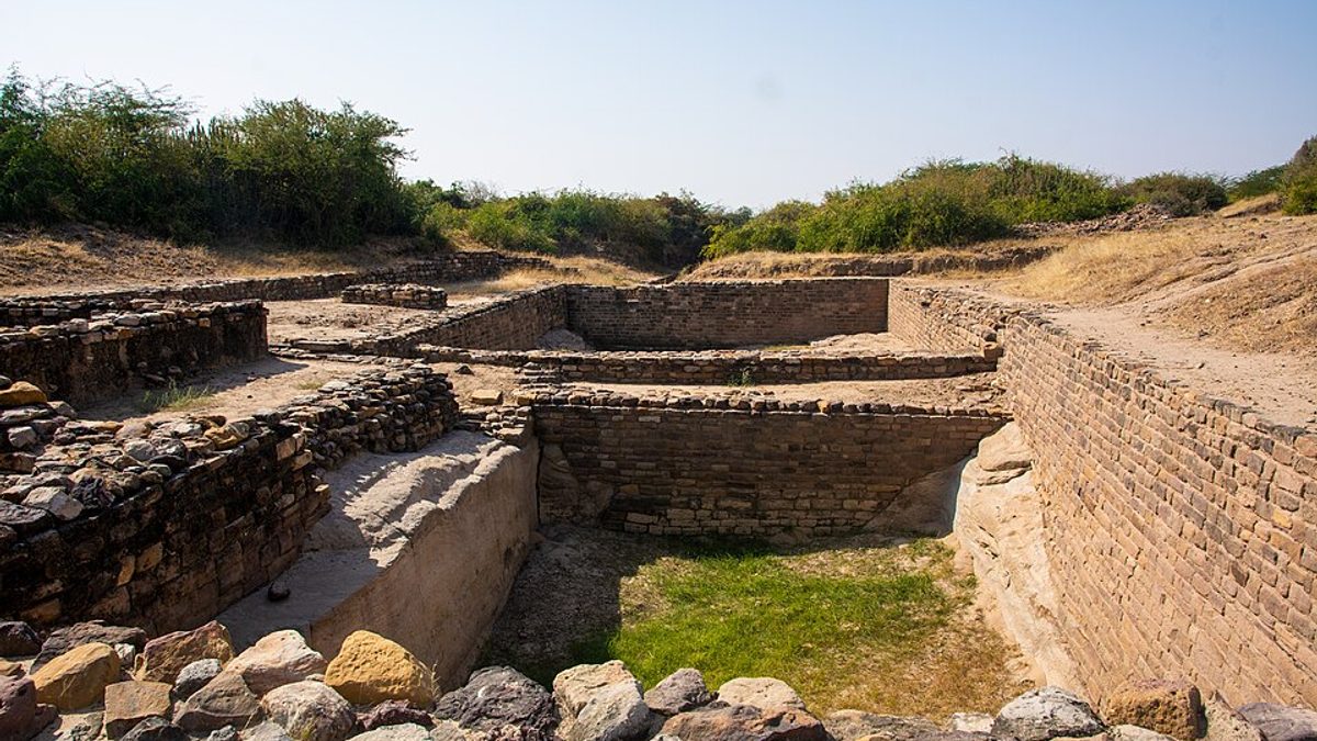 Stone walls and structures of the excavated Harappan city at Dholavira, with the wider archaeological site behind