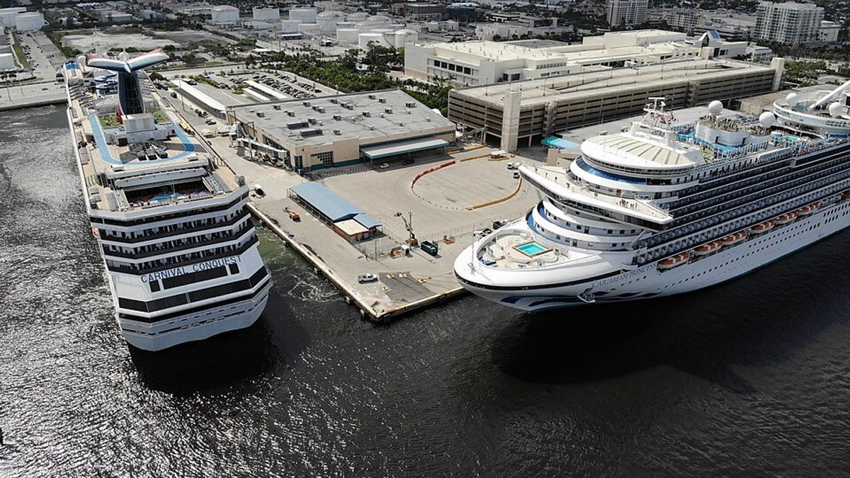 Aerial view of two cruise ships, Carnival Conquest and Caribbean Princess, berthed side by side at Port Everglades with the Fort Lauderdale skyline behind