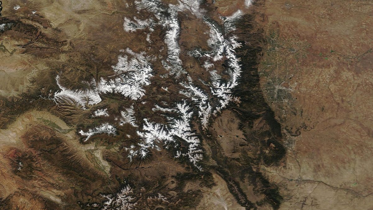 Satellite view of Colorado with the Rocky Mountains covered in snow and the eastern plains bare brown