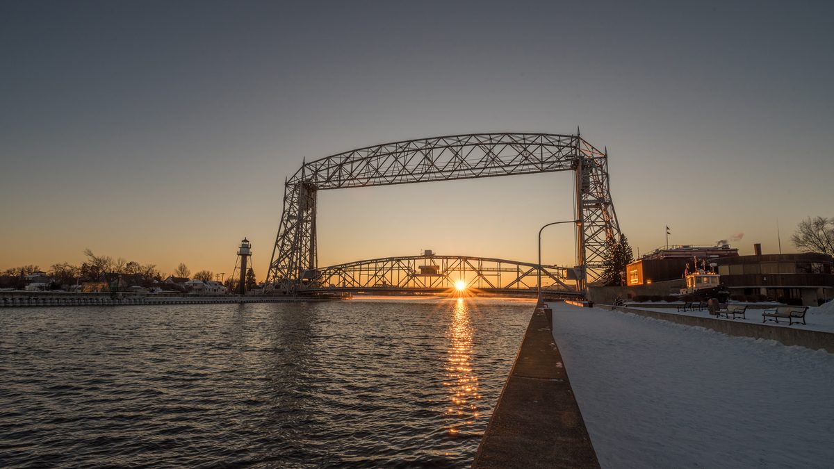 Winter sunset over the Aerial Lift Bridge and Lake Superior in Duluth, Minnesota, with snow along the shoreline
