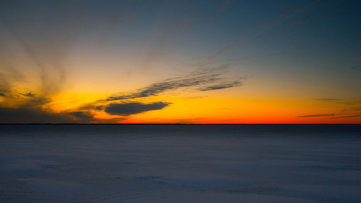 Red dusk sky over a frozen, snow-covered Lake Michigan along the Wisconsin shoreline