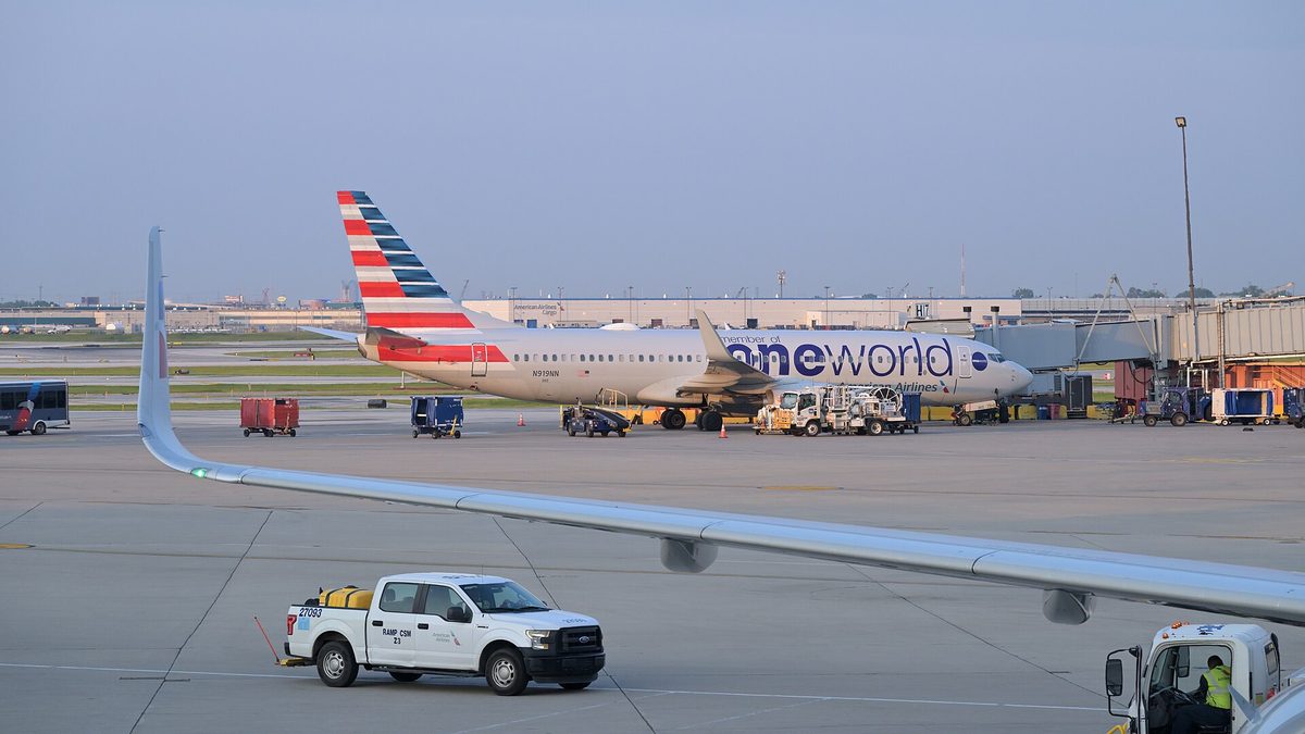 An American Airlines Boeing 737-800 at gate H17 at Chicago O'Hare with ground service vehicles beside it